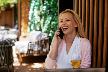 Takım elbiseli, şarap içen ve dizüstü bilgisayarla çalışan güzel bir iş kadını. İş kadını restoranda eğleniyor.