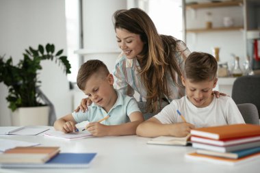 Anne oğullarıyla ödev yapıyor.