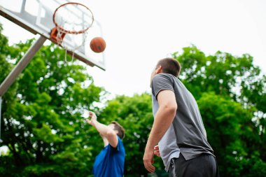 Parkta basketbol oynayan iki genç adam. Arkadaşlar dışarıda dostça bir maç yapıyor.