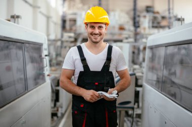 Fabrika işçisi. Genç adam fabrika ortamında çalışıyor.