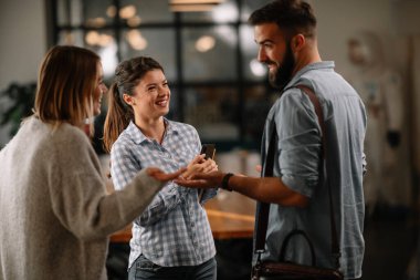 Modern açık uzay ofisinde sıradan iş adamlarından oluşan bir grup. İş kadınları ve işadamları yeni proje hakkında konuşuyor.