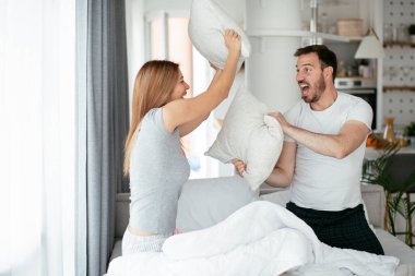 Çift evde eğleniyor, yastıklarla kavga ediyor.
