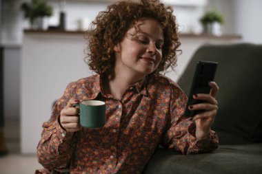 Telefonu kullanan genç bir kadın. Güzel kadın evde eğleniyor..