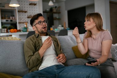 Erkek arkadaşı ve kız arkadaşı kanepede tartışıyor. Kızgın kadın erkek arkadaşına bağırıyor..