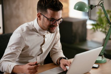 Ofiste dizüstü bilgisayarıyla çalışan bir iş adamı. Ofiste bir proje üzerinde çalışan şık bir işadamı..
