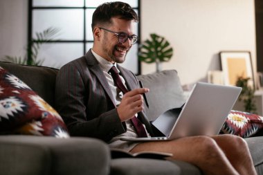 Evde pantolonsuz çalışan bir iş adamı. Genç adam video görüşmesi sırasında bilgisayarı kullanıyor..