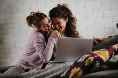 Kız arkadaşlar evde dizüstü bilgisayardan müzik dinlerler. Kızlar apartmanda eğleniyor..