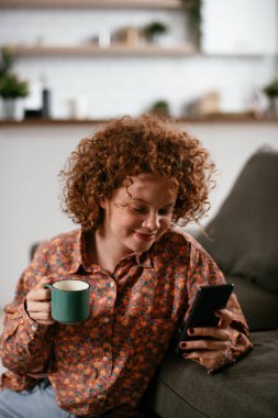 Telefonu kullanan genç bir kadın. Güzel kadın evde eğleniyor..