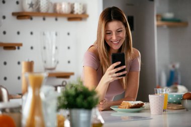 Mutfaktaki kadın. Mutfakta telefon kullanan güzel bir kadın..