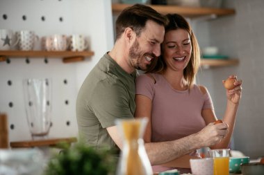 Genç çift evde kahvaltı hazırlıyor. Sevgi dolu çift mutfakta birlikte yemek pişiriyor..