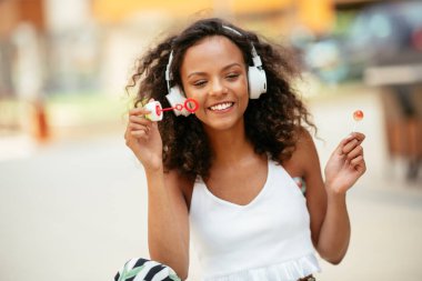 Güzel Afrikalı kız sokakta sabun köpüğüyle oynuyor.