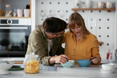 Genç çift evde kahvaltı hazırlıyor. Sevgi dolu çift mutfakta mısır gevreği yiyor..