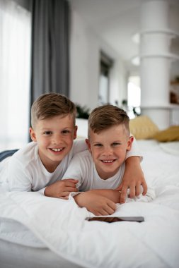 İki küçük kardeş telefonda oyun oynuyorlar. Güzel çocuklar evde eğleniyor..