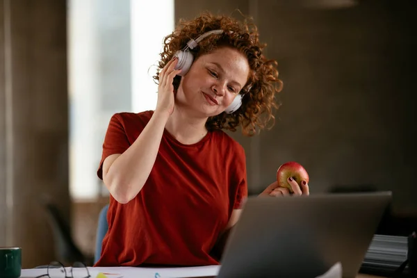 Gadis Cantik Memakai Headphone Dan Makan Apel Tempat Kerjanya — Stok Foto