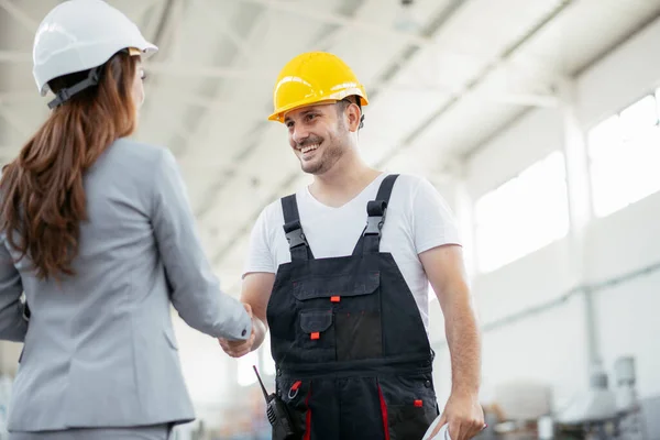 Manager and factory worker talk at production line