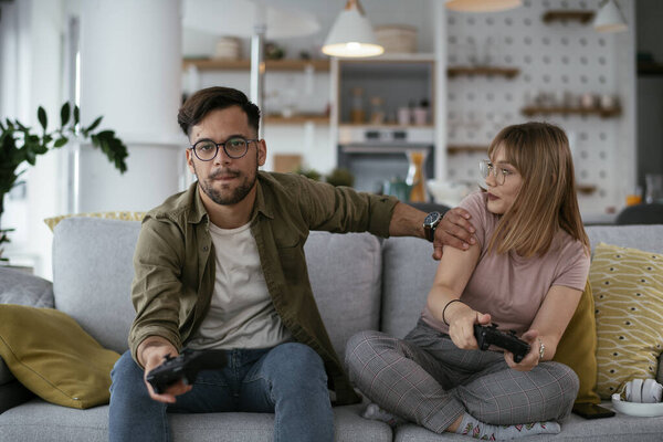 Beautiful young couple playing video games at home.
