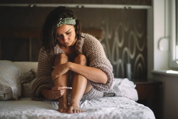 Elinde hamilelik testi olan endişeli genç bir kadın.