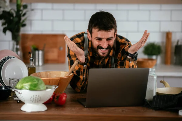 Portrait of handsome man in kitchen. Young man cooking while having video call.