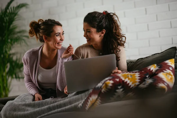 Girlfriends listen music from laptop at home. Girls having fun at apartment.