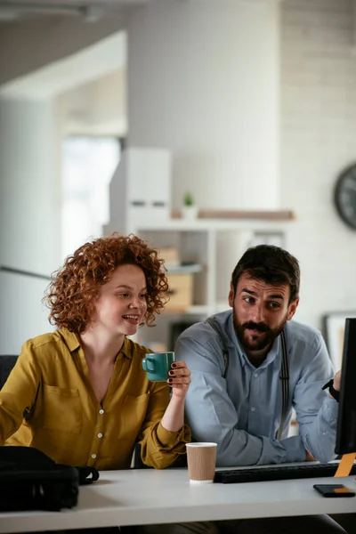 Business people in office. Businesswoman and businessman discussing work while drinking coffee.