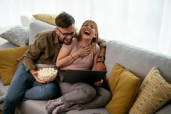 Young couple watching movie on laptop. Loving couple enjoying at home.