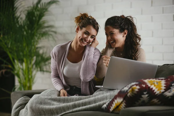 Girlfriends listen music from laptop at home. Girls having fun at apartment.