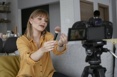 Kadın video kaydedicisi, kanalı için makyaj dersi kaydediyor. Sosyal medyada paylaşmak için makyaj dersi alan genç ve güzel bir kadın..