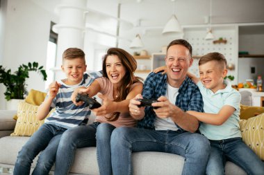 Anne ve baba evde çocuklarla video oyunu oynarken eğleniyorlar..