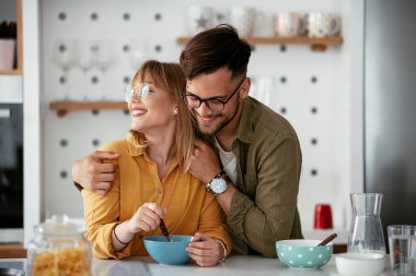 Genç çift evde kahvaltı hazırlıyor. Sevgi dolu çift mutfakta mısır gevreği yiyor..
