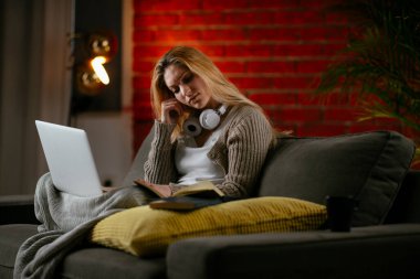 Güzel bir genç kadın evinde dizüstü bilgisayar çalışıyor ve çalışıyor..