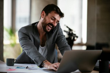 İş adamı proje üzerinde çalışıyor. Genç işadamı ofiste akıllı telefondan konuşuyor..