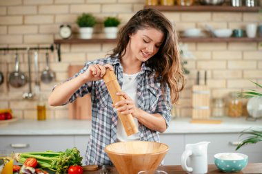 Genç kadın mutfakta yemek pişiriyor. Makarna pişiren kadın.