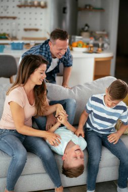 Genç bir aile evde eğleniyor. Mutlu ebeveynler ve çocuklar eğleniyor..