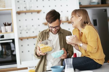Genç çift evde kahvaltı hazırlıyor. Sevgi dolu çift mutfakta mısır gevreği yiyor..