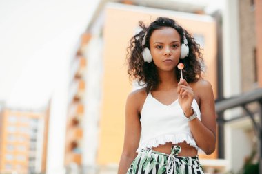 Dışarıda güzel bir kadın var. Genç Afrikalı bir kadın telefon kullanarak bankta oturuyor..