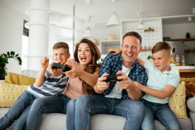 Anne ve baba evde çocuklarla video oyunu oynarken eğleniyorlar..