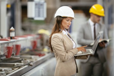 Fabrika müdürü ve mühendisi teftiş yapıyor. İş adamı ve işkadını üretim hattında.