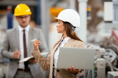 Fabrika müdürü ve mühendisi teftiş yapıyor. İş adamı ve işkadını üretim hattında.