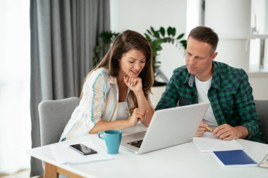 Erkek ve kadın evde dizüstü bilgisayar kullanarak çalışıyor.