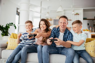 Anne ve baba evde çocuklarla video oyunu oynarken eğleniyorlar..