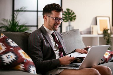 Evde pantolonsuz çalışan bir iş adamı. Genç adam video görüşmesi sırasında bilgisayarı kullanıyor..