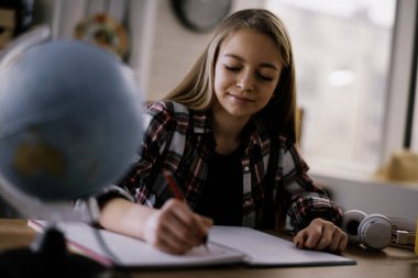 Güzel küçük kız evde ders çalışıyor.