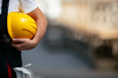 Sarı miğferi elinde tutan fabrika işçisi