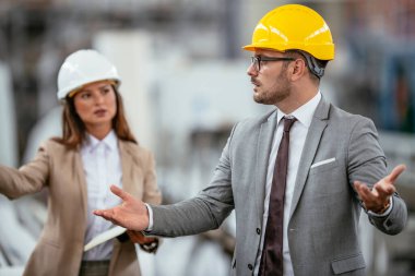 Fabrikadaki iş adamı ve iş kadını. Fabrika üretim hattında kalite kontrolde çalışan iki profesyonel insan..