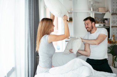 Çift evde eğleniyor, yastıklarla kavga ediyor.