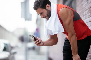 Genç sporcu dışarıda koşuyor. Açık hava eğitiminden sonra yakışıklı bir adam dinleniyor..