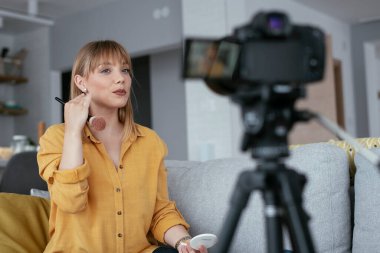 Kadın video kaydedicisi, kanalı için makyaj dersi kaydediyor. Sosyal medyada paylaşmak için makyaj dersi alan genç ve güzel bir kadın..