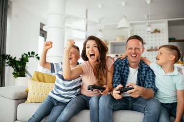 Anne ve baba evde çocuklarla video oyunu oynarken eğleniyorlar..