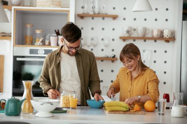 Genç çift evde kahvaltı hazırlıyor. Sevgi dolu çift mutfakta eğleniyor..