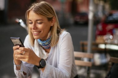 Kafede mesajlaşan genç kadın.